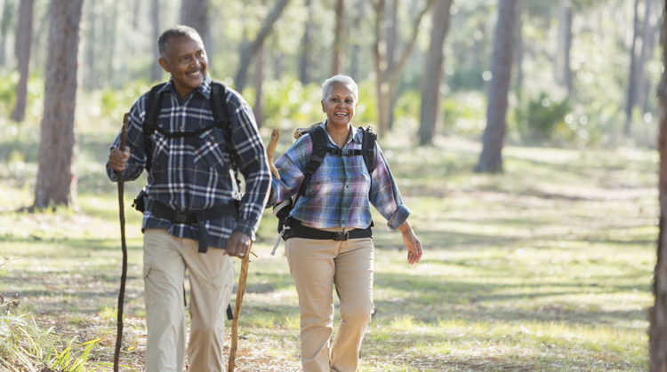 An older couple walking outside in the woods for exercise.